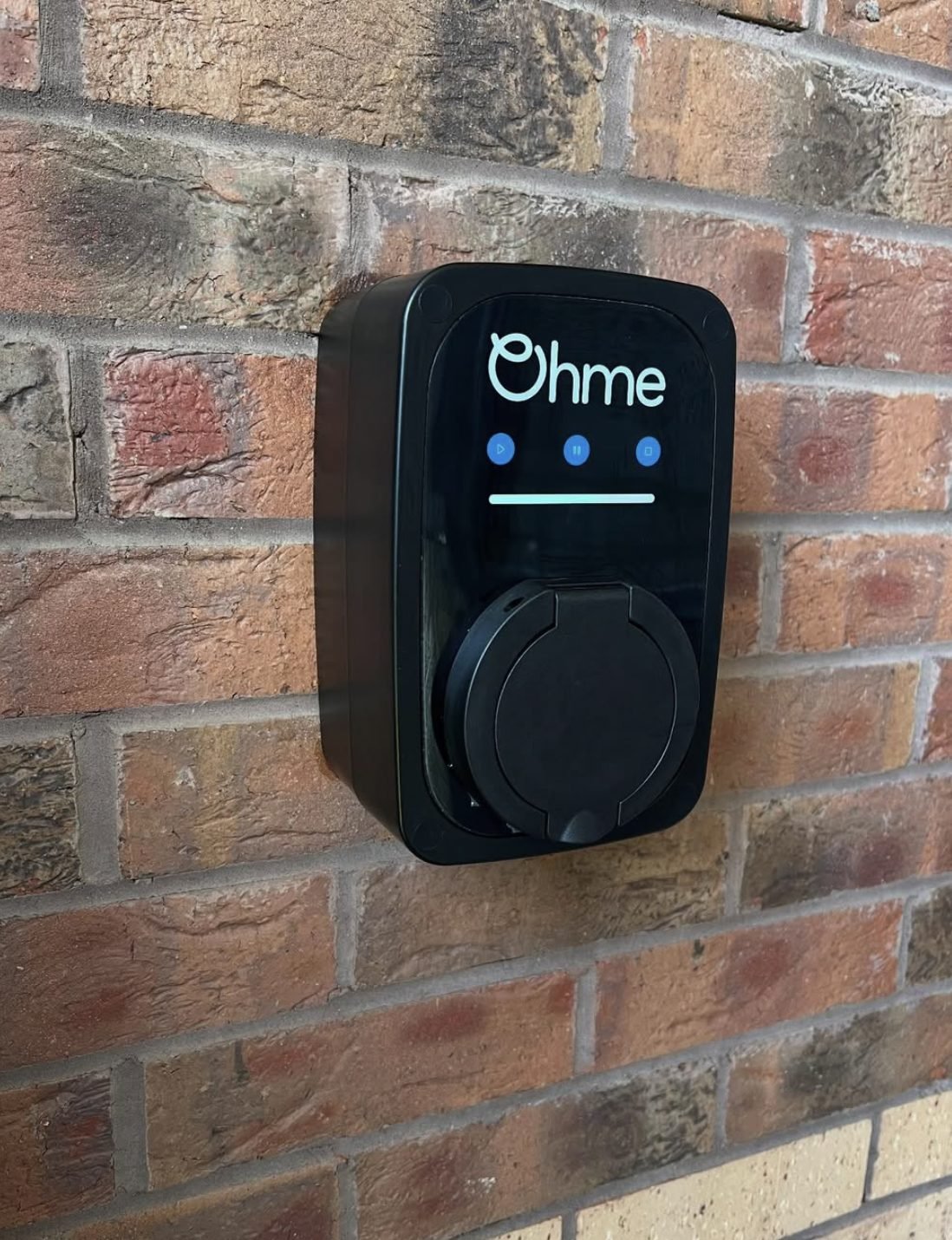 Ohme EV charge point installed on a brick house wall